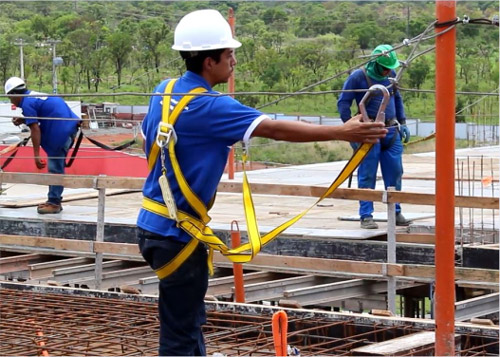 Trabalhador com cinto paraquedista conectado a sistema de linha de vida em canteiro de obras